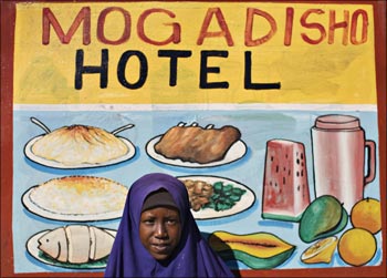 A Somali girl stands in front of a restaurant sign board in Mogadishu, Somalia's capital city.