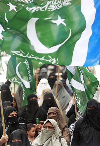 Female supporters of Jamaat-e-Islami, a Islamic political party, wave their party flags while marching through the streets of Karachi.
