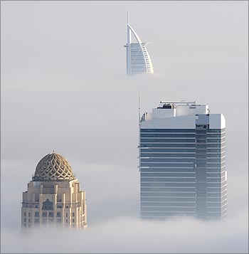 The Burj Al Arab hotel (rear) towers above heavy fog in Dubai.