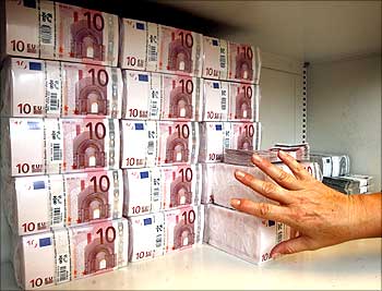 A bank clerk places a pack of 10 Euro notes valuing 10,000 Euros.