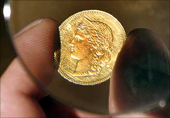 A man holds a golden 20 Swiss francs coin, printed in 1895, under a magnifier in Zurich.