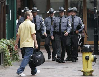 A pedestrian walks towards a group of Pennsylvania State Troopers as they patrol downtown Pittsburgh.