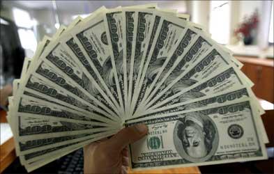 An employee displays US dollars at a counter.