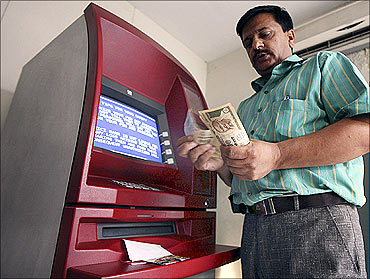 A man counts money after withdrawing it from an ATM in Jammu.