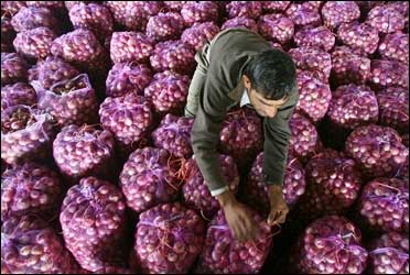 A worker packs onion bags at a wholesale vegetable market in Chandigarh.