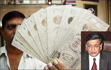 A jeweller displays silver plates in the form of Indian rupee notes. Sunil Mitra (inset).
