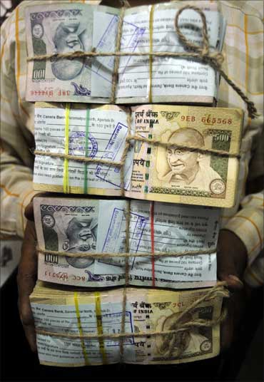 An employee carries bundles of Indian currency notes inside a bank in Agartala, capital of Tripura.