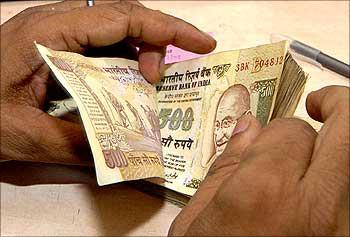 A cashier counts currency notes inside a bank.