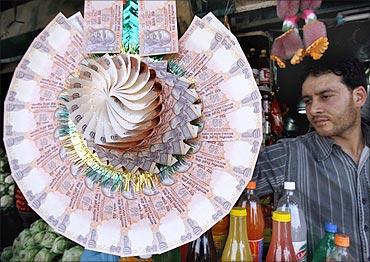 A Kashmiri shopkeeper displays a garland made of Indian currency notes at a market in Srinagar.