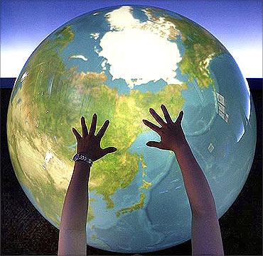 A visitor places her hands on a Tangible Earth, a digital globe.