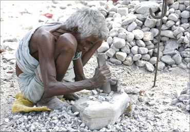 Fulchori Debnath, 70, a woman labourer breaks stones on the banks of river Balason, in West Bengal.