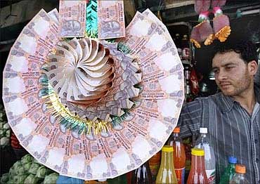 A Kashmiri shopkeeper displays a garland made of Indian currency notes at a market in Srinagar.