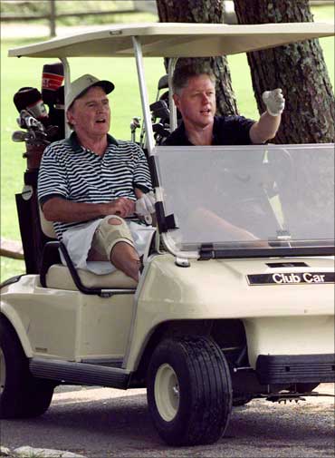 The then US president Bill Clinton explains the layout of the first hole to General Electric CEO Jack Welch (L).