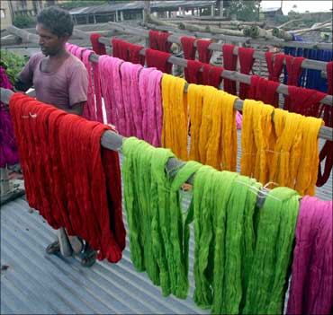 A worker arranges coloured skeins of yarn on a roof at a hand-dyeing factory.