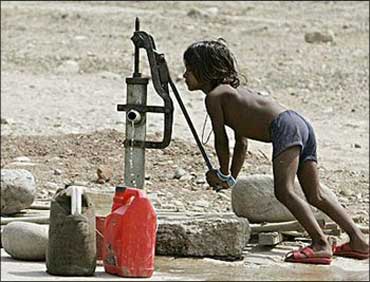 A child works a water pump to draw some water.
