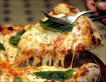 A slice of pizza is served at a pizzeria.