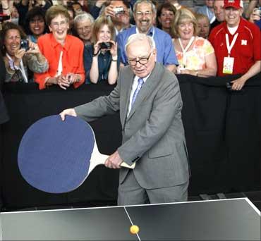 Warren Buffett plays table tennis using a giant paddle.