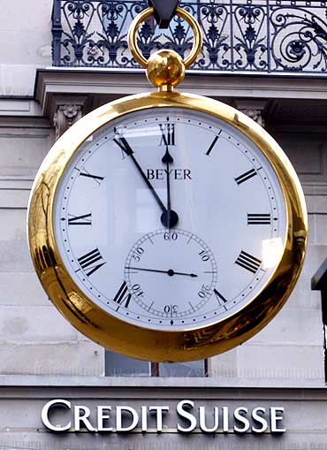 A giant watch displays the time in front of the logo of Swiss Credit Suisse bank.