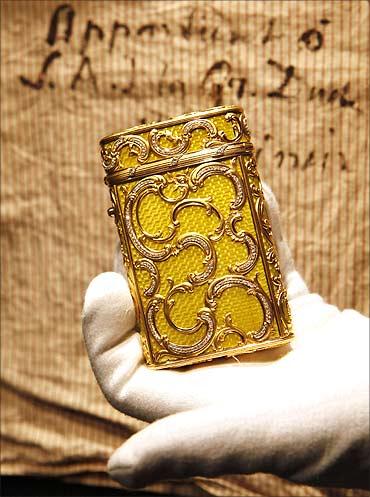 A worker holds a Faberge jewelled gold and enamel cigarette case by Michael Perchin in London.