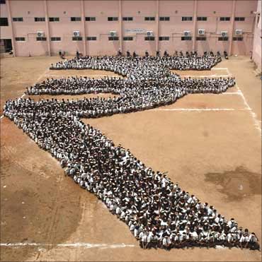 Students make a formation of the Indian rupee symbol.