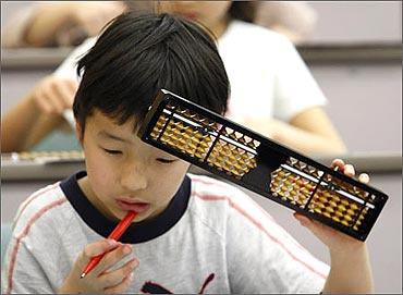 An elementary school boy holds a Japanese traditional calculating tool called the soroban (abacus).