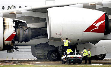 Technicians work next to the damaged engine of a Qantas Airways A380 passenger plane.