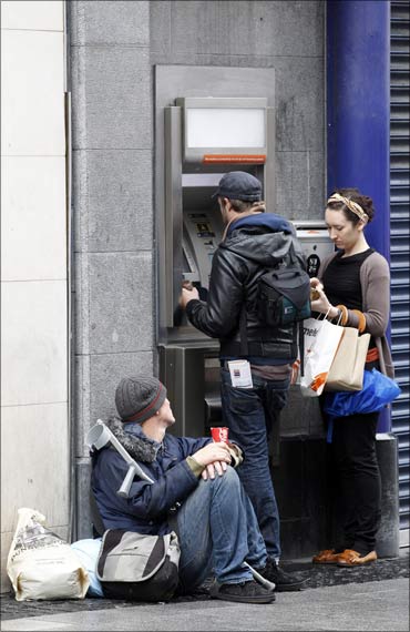 A beggar sits next to a cash machine in the centre of Dublin.