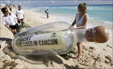 Activists of Oxfam carry a giant bottle on the shores of a beach in Cancun. The bottle contains a message reading 'Urgent: Save Lives in Cancun', in reference to millions of world's poorest people. Photograph: Stringer/Reuters