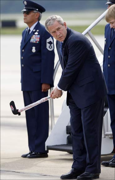 Former US President George W. Bush swings a hockey stick on the tarmac of Raleigh-Durham Airport.