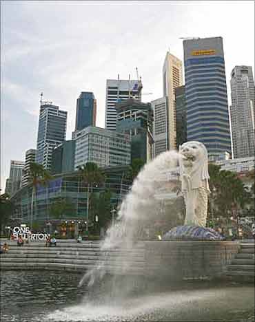 People sit on the steps near the Merlion, in Singapore's financial district.