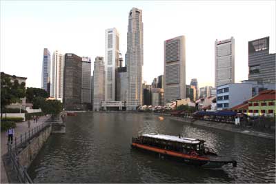A tour boat travels up Singapore River past the skyscrapers of the financial district.
