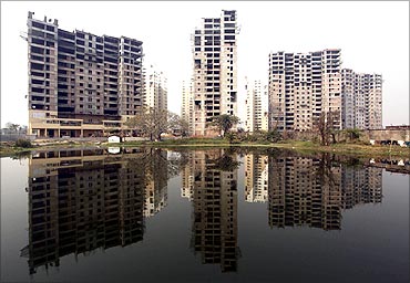 Residential apartments under construction are reflected on the surface of a pond in Kolkata.