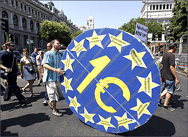 A demonstrator from Spain's 15M movement rolls a giant wheel symbolizing euro.