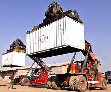 Workers prepare to stack containers using cranes at Thar Dry Port in Sanand in Gujarat.