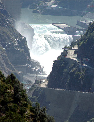 Water flows on the banks of Chenab River with the Baglihar hydroelectric project in the background.