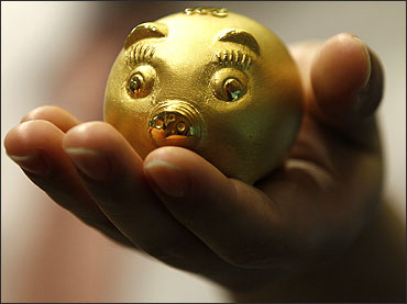 An employee of a jewellery shop holds a 112.5 gram-weight gold pig.