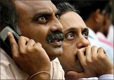 Investors look at a large screen displaying Sensex figures on the facade of BSE building.