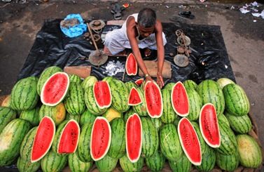 A vendor arranges watermelons for sale in a pavement stall in Kolkata.