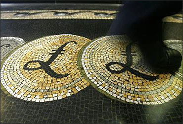 An employee is seen walking over a mosaic of pound sterling symbols set in the floor of the front hall of the Bank of England.