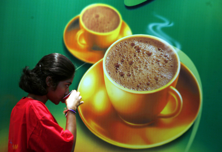 A visitor drinks coffee at the International Coffee Festival in Bangalore.