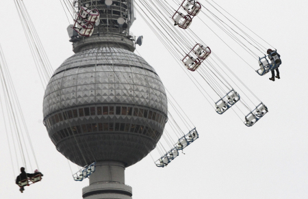 People ride a merry-go-round in a Christmas market, in front of the television tower in Berlin.