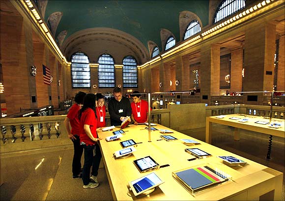 Employees look at iPad tablets on display inside the newest Apple Store in New York City's Grand Central Station.