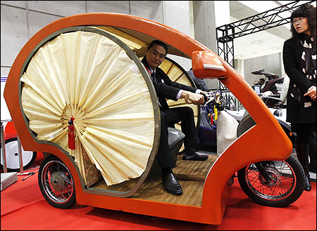 An employee of Japan's Electronic Vehicle maker Yodogawa, poses in its EV car Meguru.