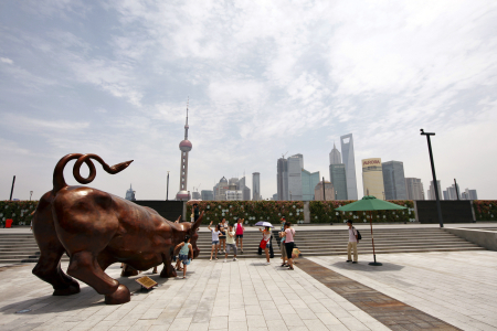 People pose next to the Charging Bull statue in Shanghai.