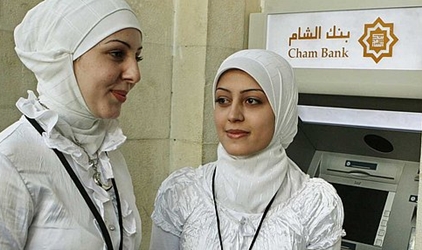 Employees of Cham bank, a newly opened Islamic bank, stand in front of an ATM machine.