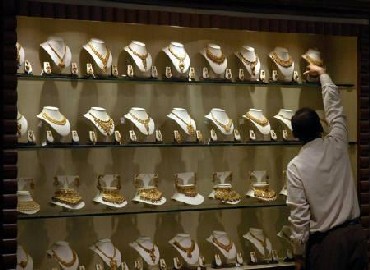 A salesman arranges gold necklaces at a jewellery showroom.