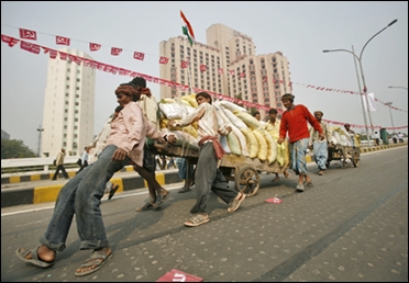 Labourers try to slow down a hand cart loaded with sacks of sand at a flyover in New Delhi.