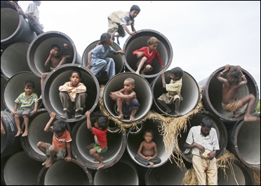 Children play in water pipes at a construction site on the banks of the Yamuna River.