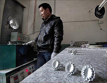 An employee melts metal as he stands next to replicas of the British royal engagement ring.