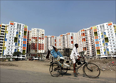 A man rides his cycle rickshaw past newly-constructed residential buildings.